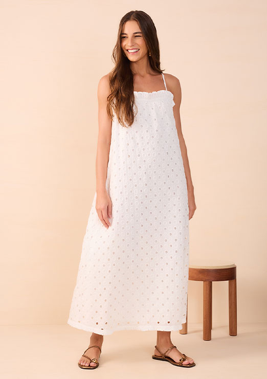 Modelo morena de cabelos castando usando vestido branco midi de alcinha e solto, da coleção de alto verão da marca Dress To.