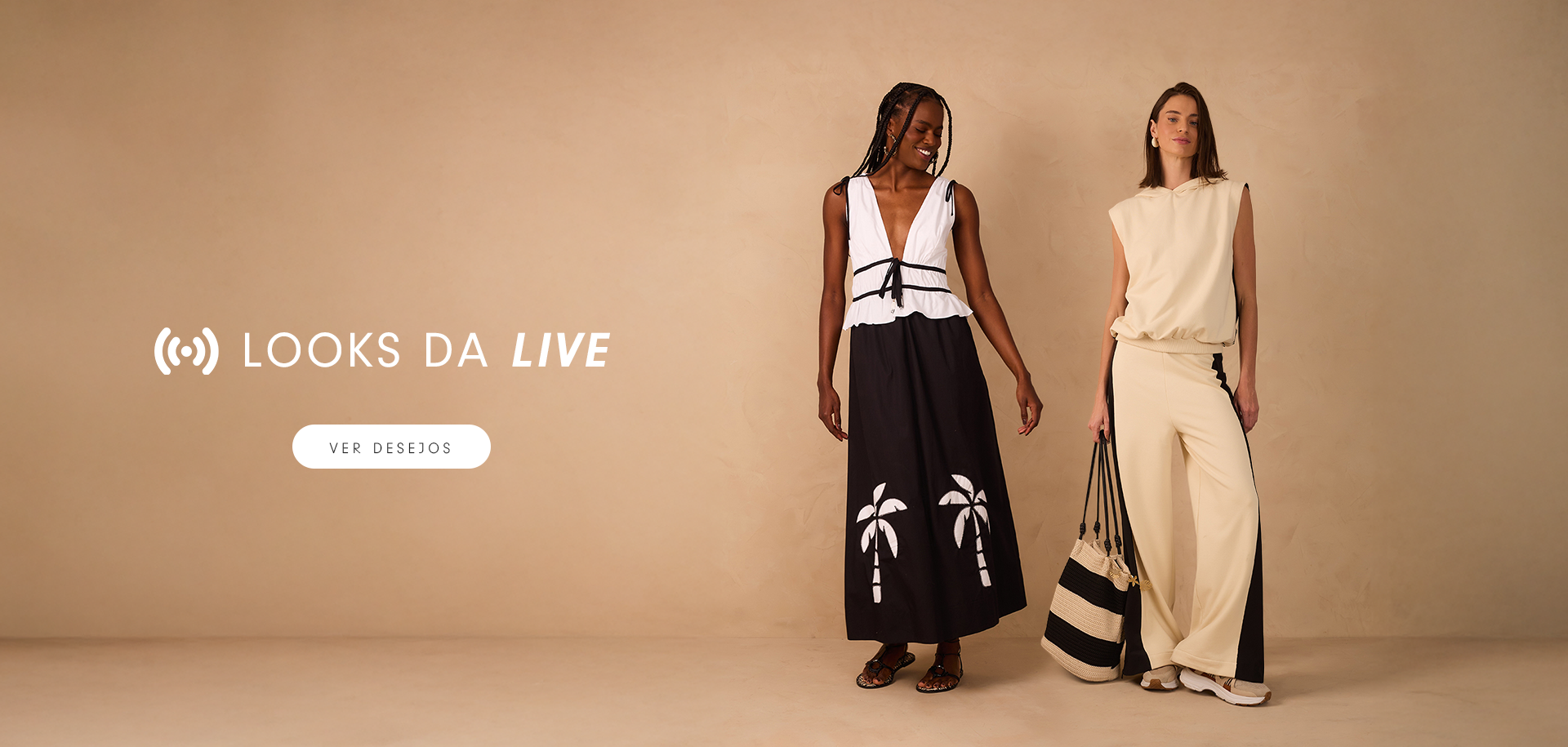 Duas modelos posam contra um fundo bege, exibindo looks da coleção “Looks da Live”. A modelo à esquerda veste um vestido longo preto com estampa de coqueiros brancos e parte superior branca com decote profundo e amarração na cintura. A modelo à direita usa um conjunto bege esportivo com detalhes pretos e carrega uma bolsa listrada em preto e bege. À esquerda da imagem, o texto “Looks da Live” é destacado com um botão abaixo escrito “Ver desejos”.