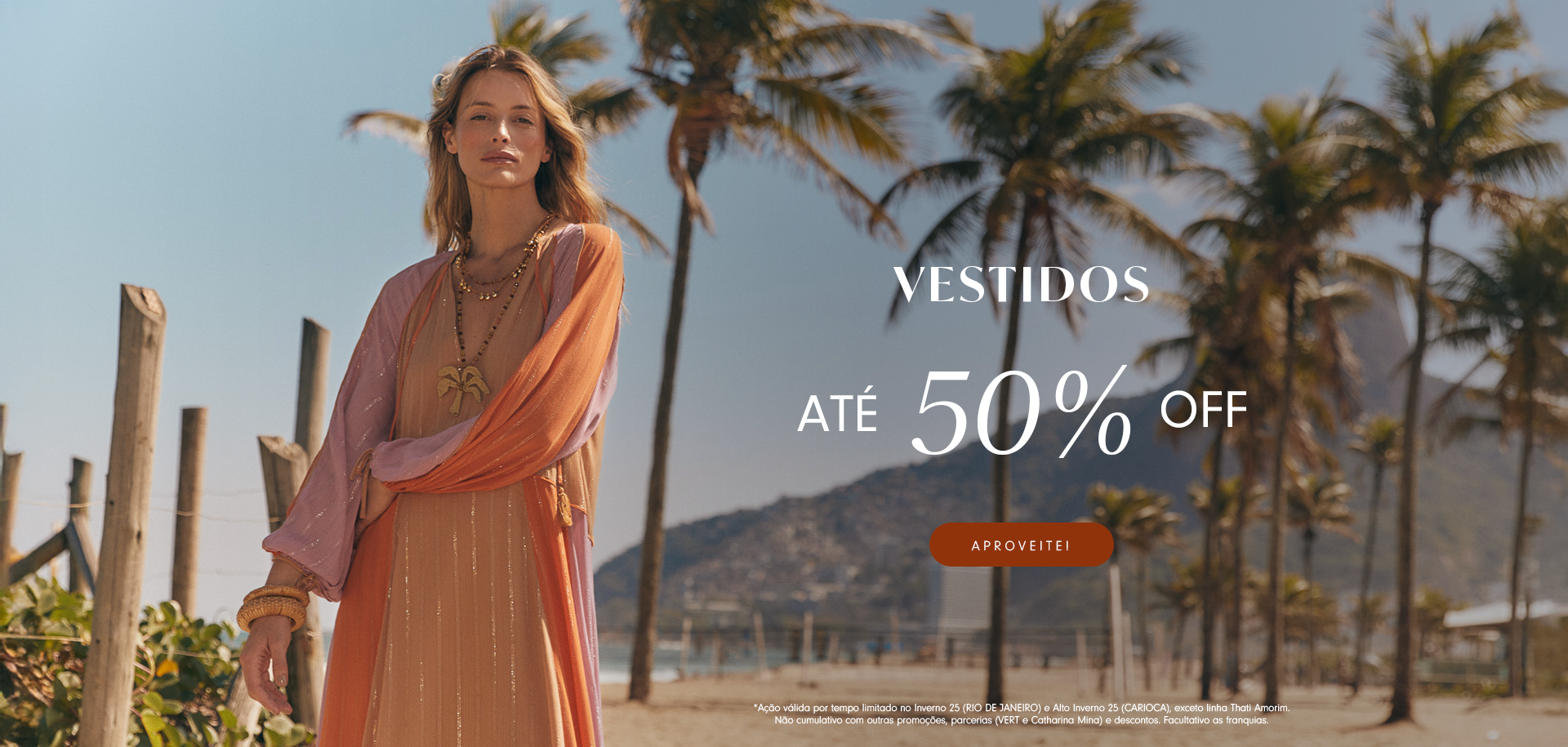 Banner promocional em cenário de praia com modelo loira vestindo um look leve em tons de laranja e rosa, com colares e pulseiras. Ao lado direito da imagem está o texto "VESTIDOS - ATÉ 50% OFF" com botão "Aproveite!". Ao fundo, palmeiras e montanhas completam o visual tropical. Texto de rodapé detalha as condições da promoção.