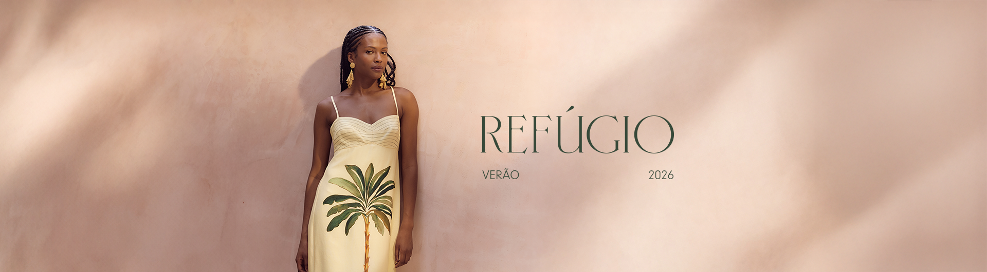 Banner campanha do lançamento da Coleção Refúgio 2026. O banner de cor clara com a modelo à esquerda usando o nosso Vestido Midi Linho Estampa Tropicana. Ao lado, mais ao centro, em fonte maior o nome da coleção "Refúgio" e abaixo os dizeres "Verão 2026".