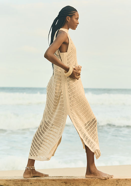 Modelo negra usando trança e vestido de tricot na cor bege.