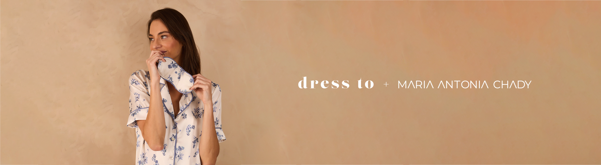 Banner da collab Dress To + Maria Antonia Chady. À esquerda, mulher usando pijama de cetim branco com estampa floral azul segura uma máscara de dormir combinando. À direita, fundo bege com os nomes das marcas centralizados em branco.