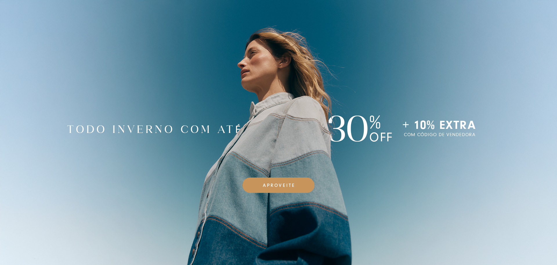 Mulher usando casaco jeans em tons claros e escuros, olhando para o horizonte sob um céu azul. Texto promocional diz 'Todo inverno com até 30% off + 10% extra com código de vendedora'. Botão laranja com a palavra 'Aproveite'.