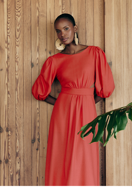 Modelo negra usando vestido vermelho de manga bufante.