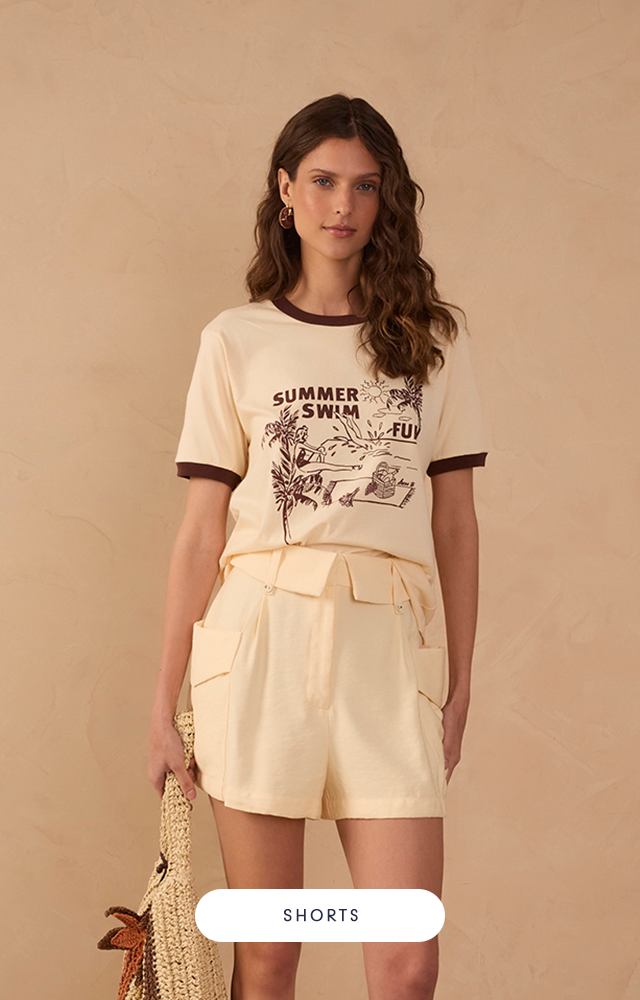 Modelo negra usando tranças com vestido de tricot na cor caramelo e sandálias na cor marrom. O botão é na cor branco.