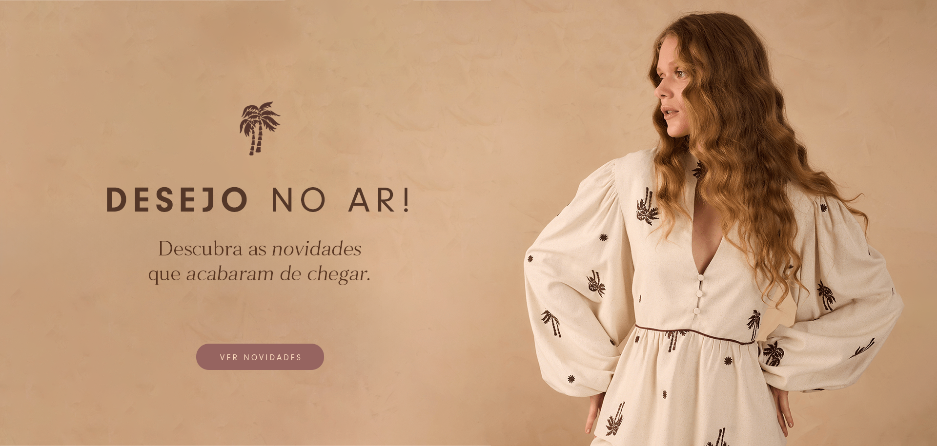 Mulher com cabelo ruivo ondulado, vestindo vestido bege claro com bordados escuros de coqueiros e mangas bufantes, posa diante de fundo bege texturizado. À esquerda, texto: 'Desejo no ar! Descubra as novidades que acabaram de chegar'. Abaixo, botão 'Ver novidades'.